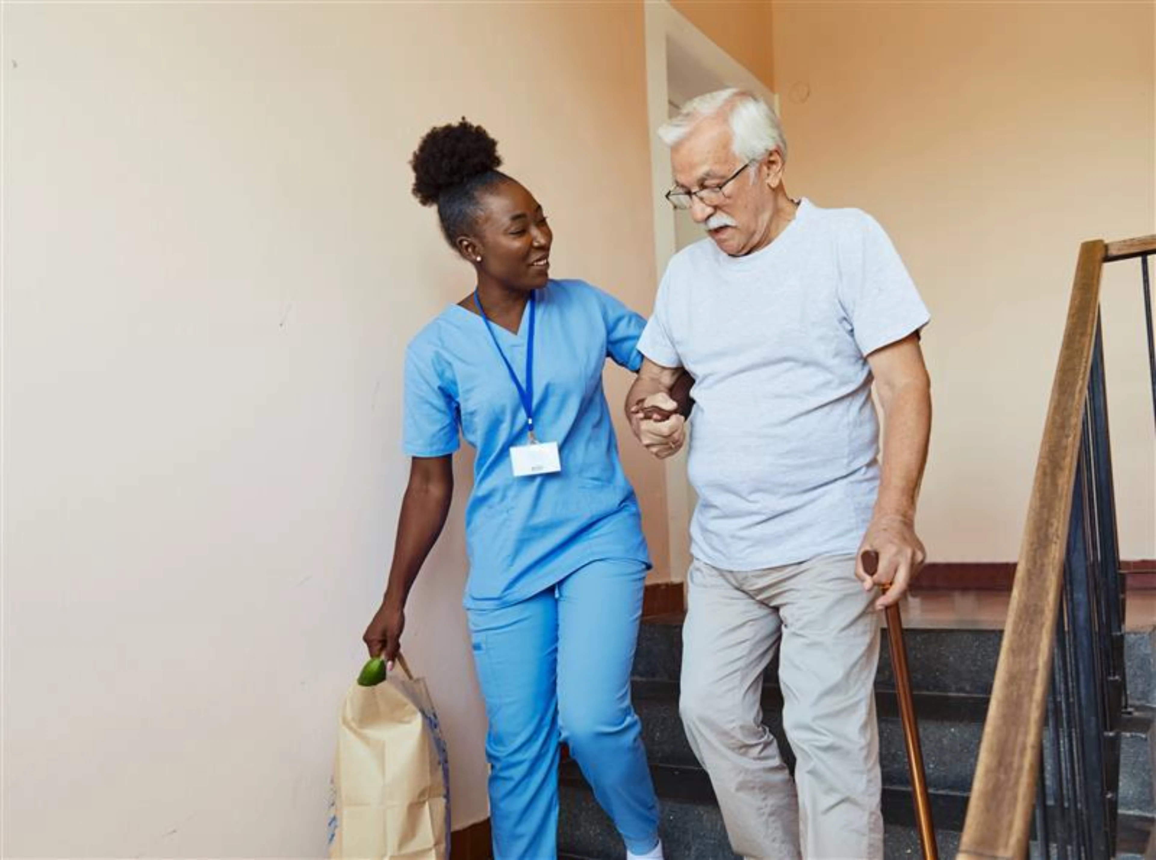 A nurse helping an elderly person down the stairs.