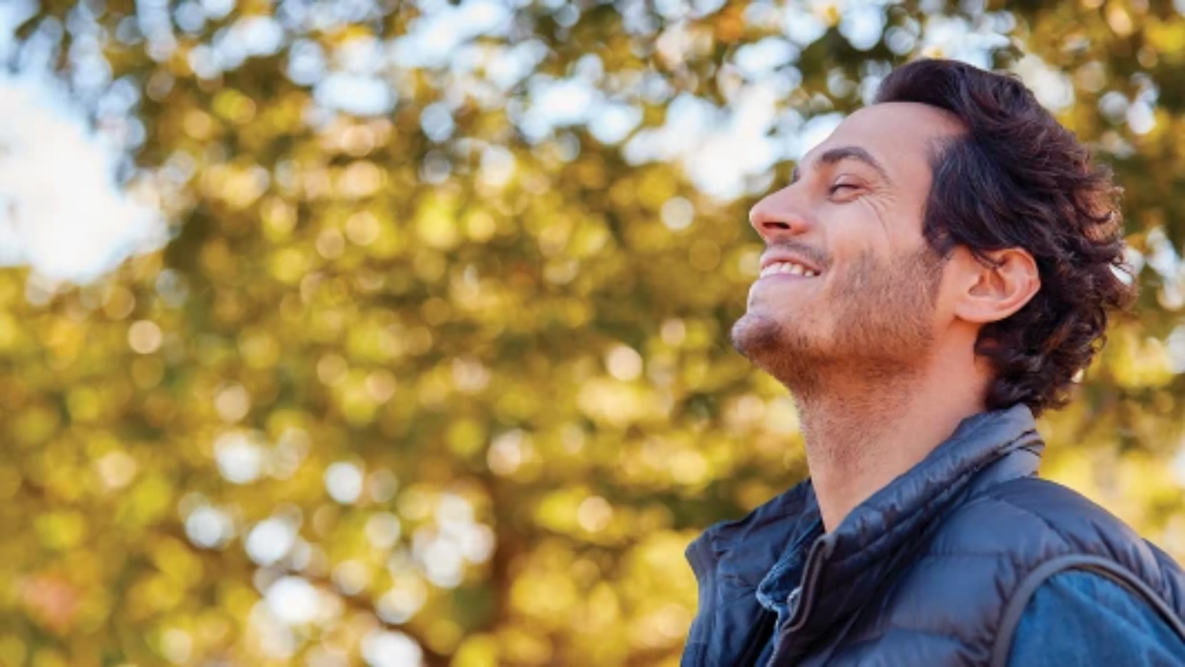 Un homme souriant à l’extérieur en train de respirer profondément dans le parc d’automne