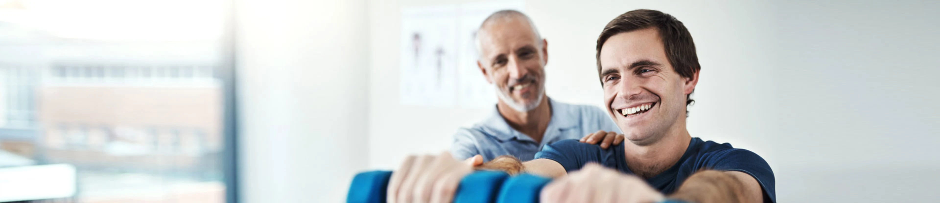 Un physiothérapeute guide un patient dans l’exécution de son mouvement dans le cadre d’une séance d’activité physique adaptée.