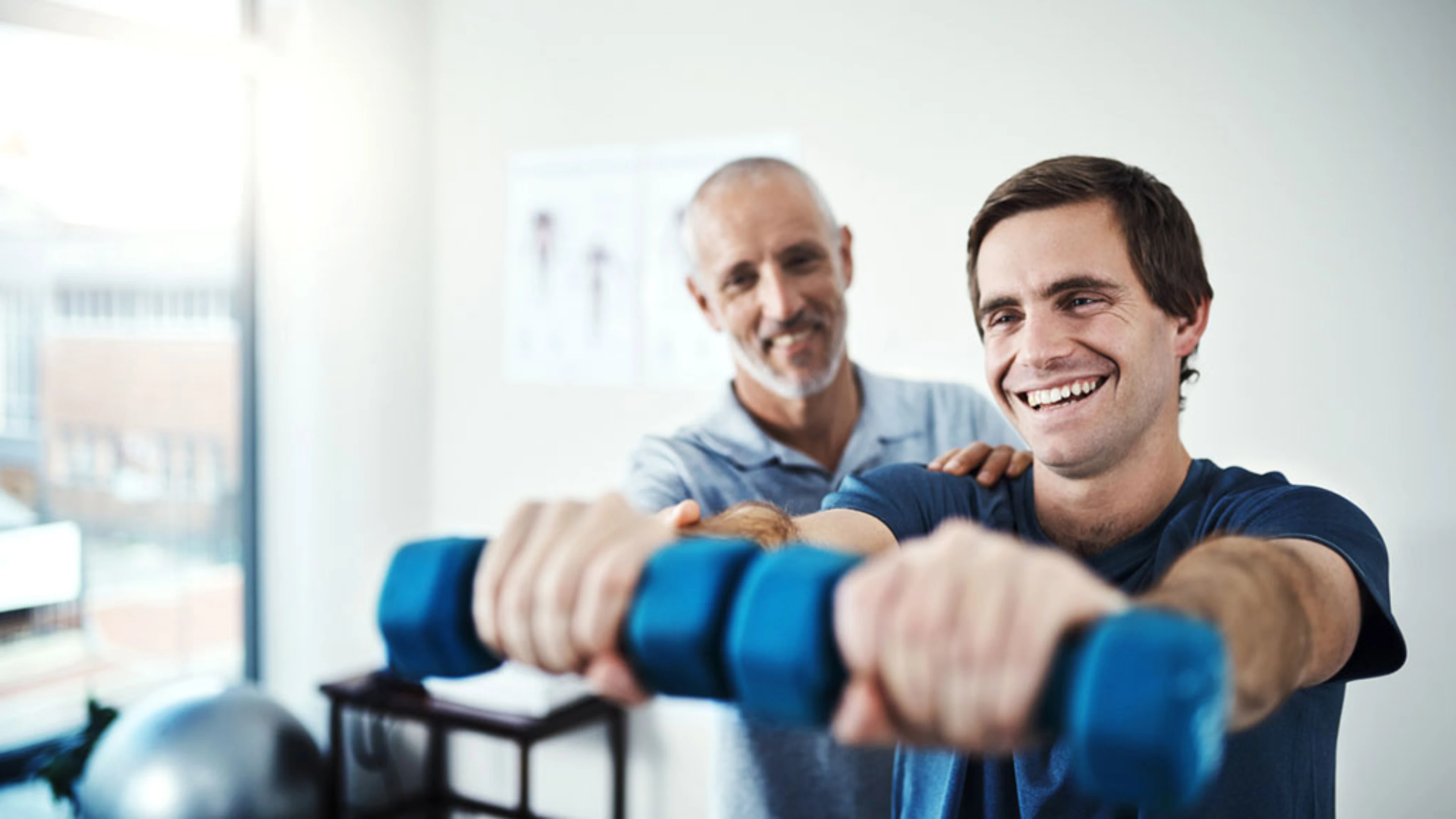 Un physiothérapeute guide un patient dans l’exécution de son mouvement dans le cadre d’une séance d’activité physique adaptée.
