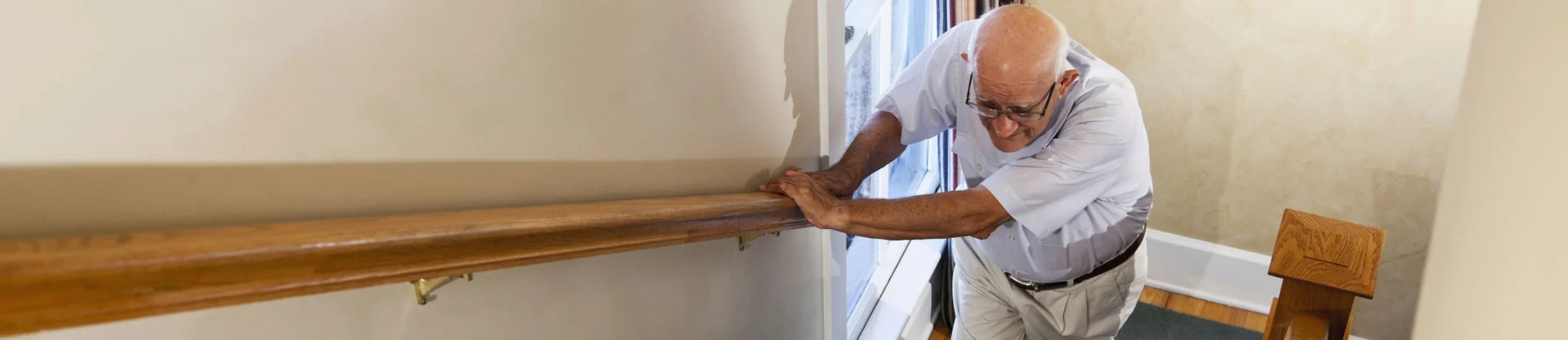 Homme rencontrant des difficultés à monter les escaliers en raison de sa maladie neuromusculaire qui impacte sa mobilité.