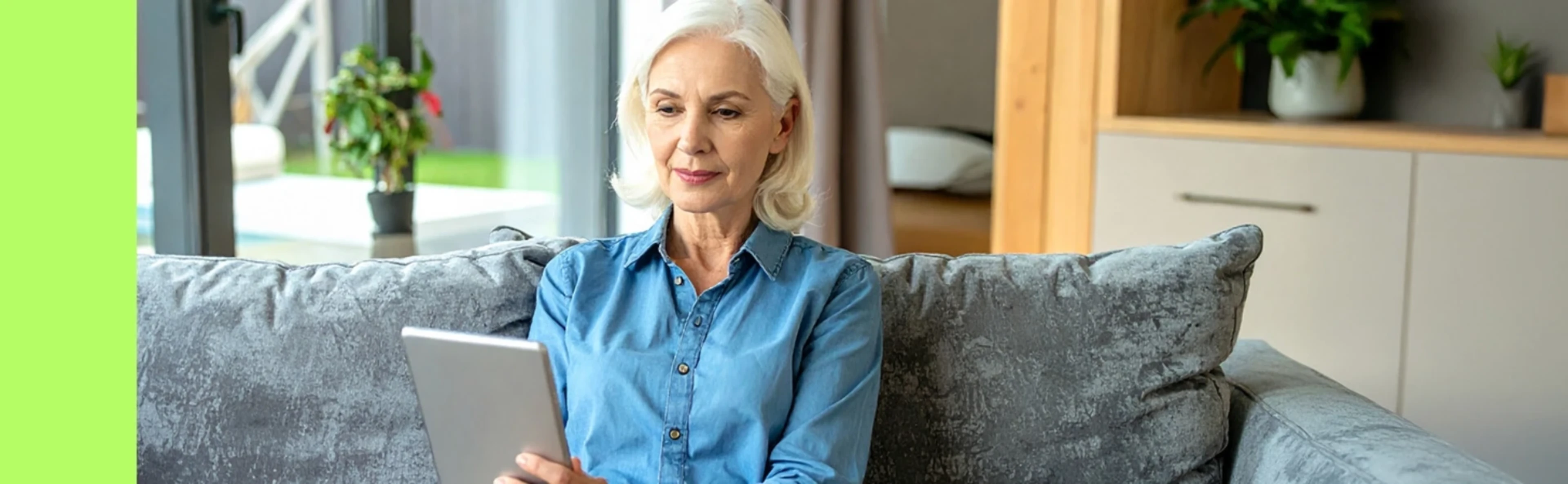 Eine ältere Frau sitz mit einem Tablet auf der Couch und informiert sich über ITP Symptome