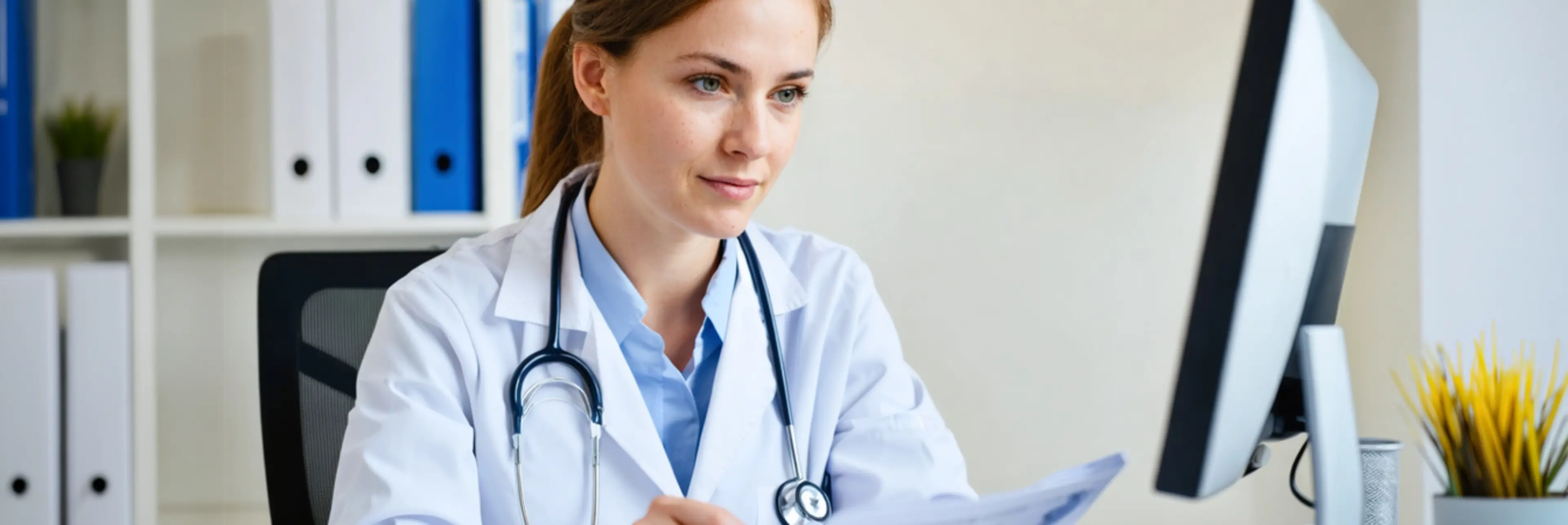 Doctor in white coat reviewing medical document at desk in modern healthcare office