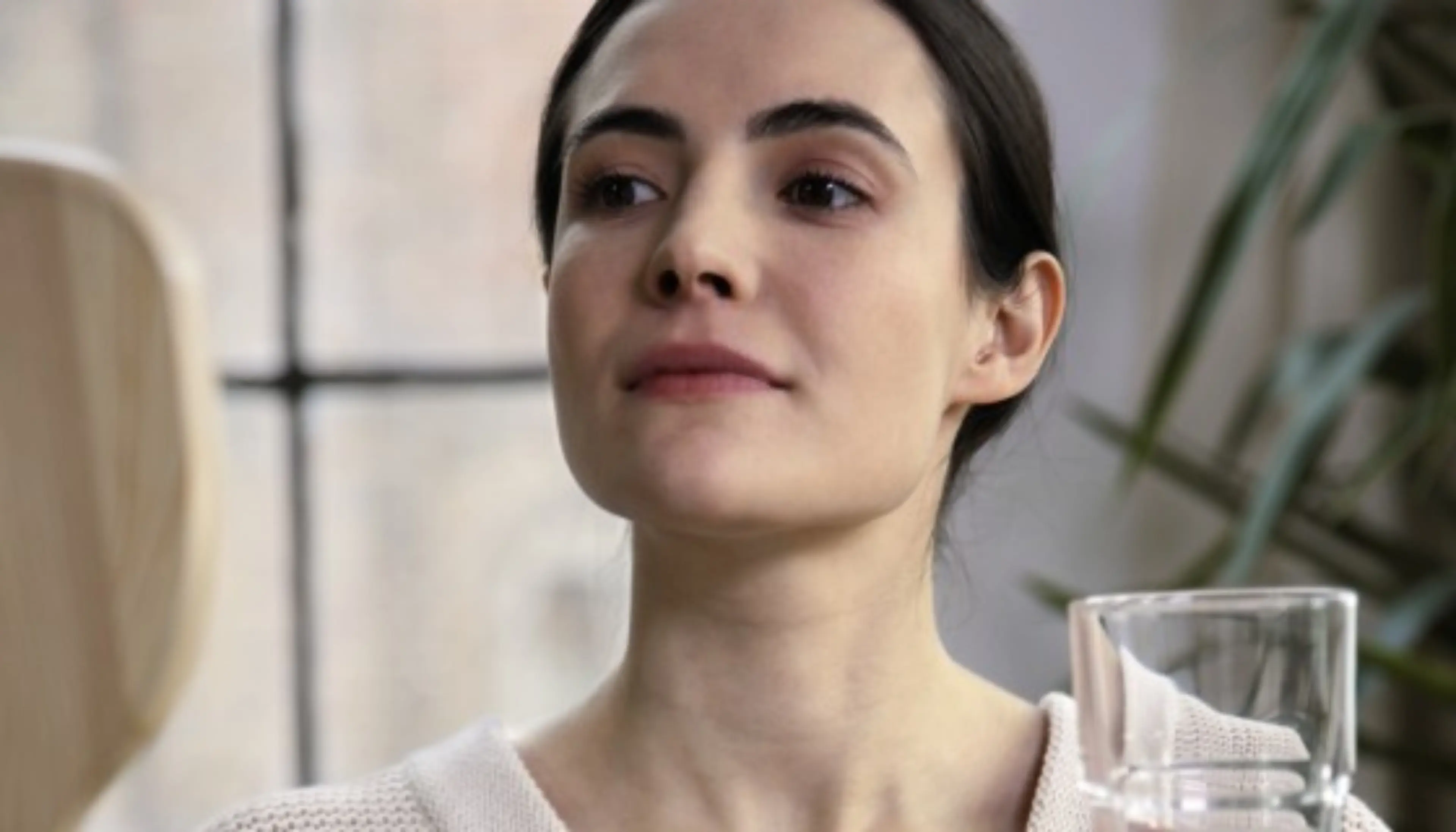 Vorbereitung auf den Schlucktest: Eine Frau hält ein Glas Wasser und einen Spiegel in den Händen.