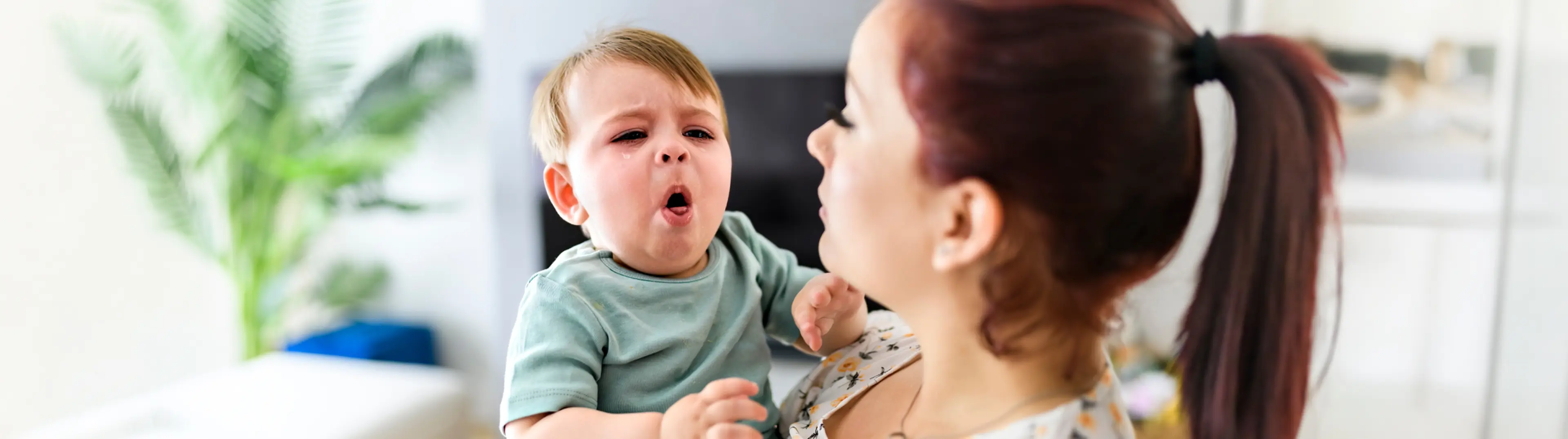Frau hält hustendes Baby im Arm