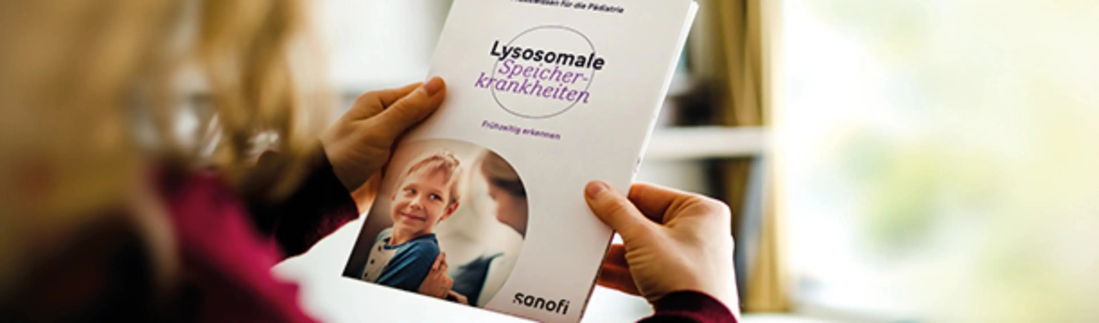 Person hält eine Broschüre von Sanofi zu lysosomalen Speicherkrankheiten