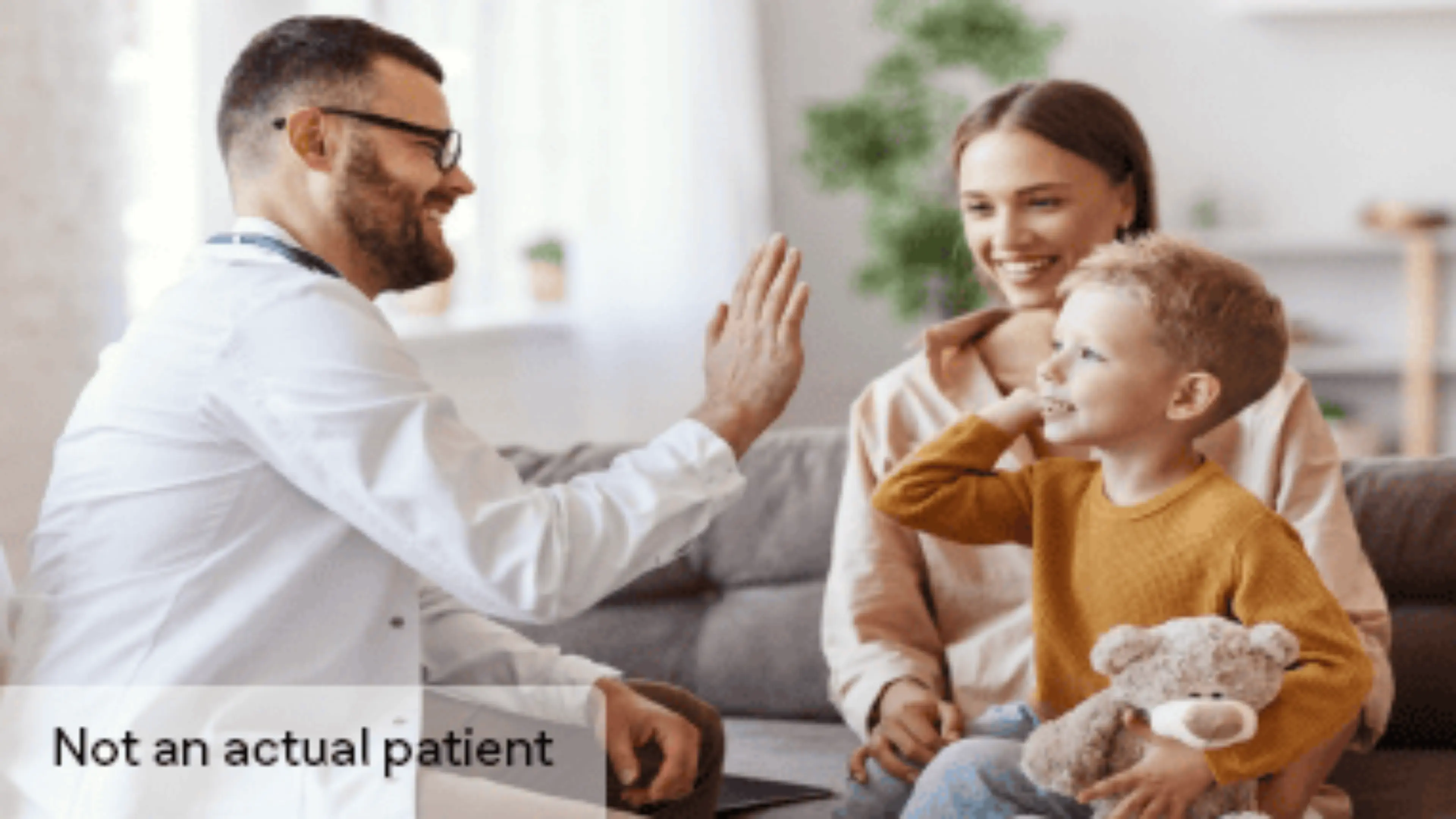 Doctor giving high five to a child wit his mother watching