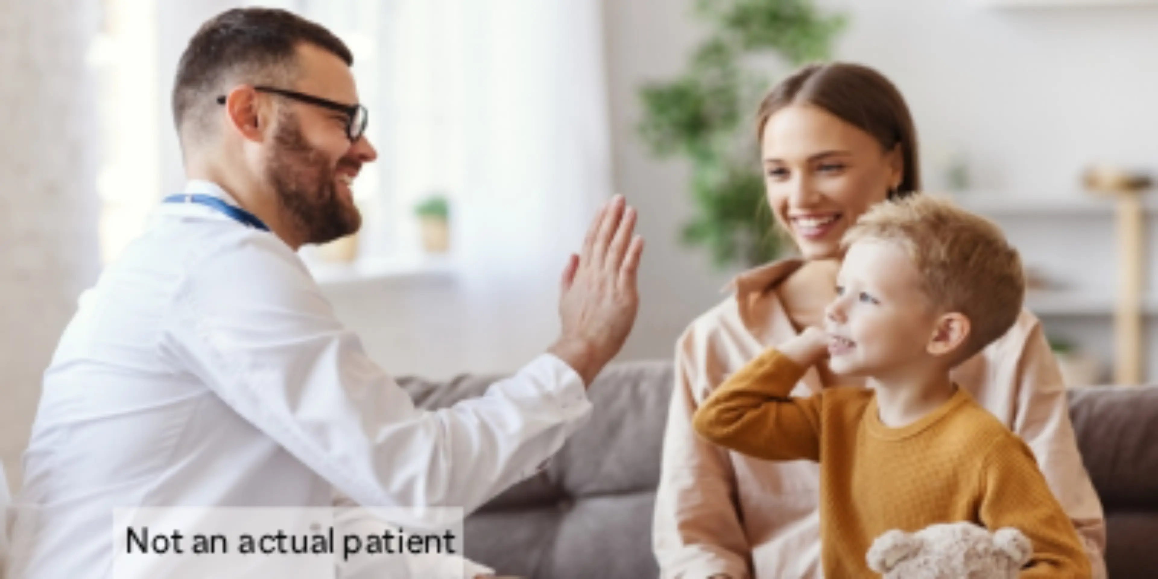 Doctor giving high five to a child wit his mother watching