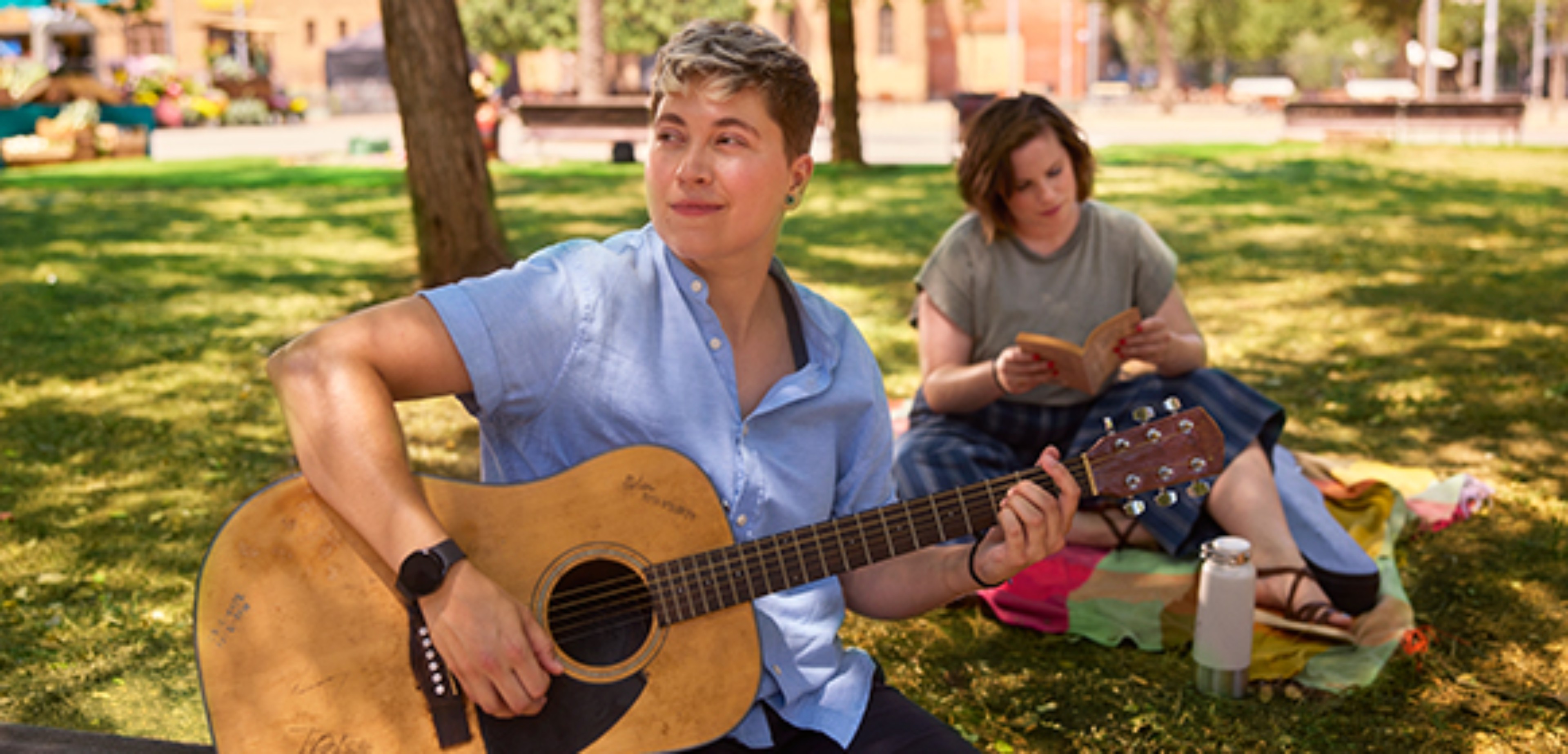 Two people playing guitar in the park