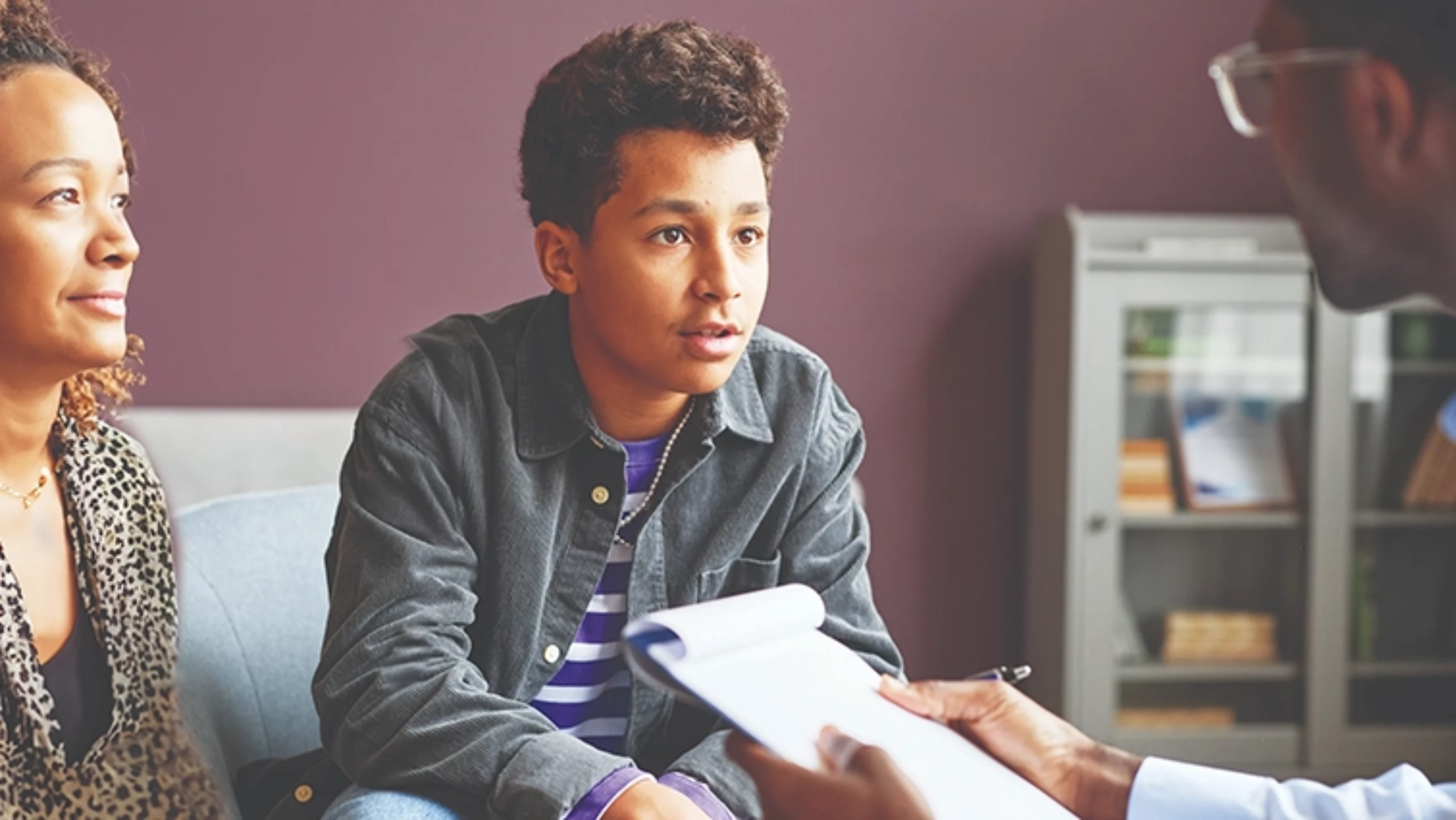 Young man speaking to a healthcare professional in an office.