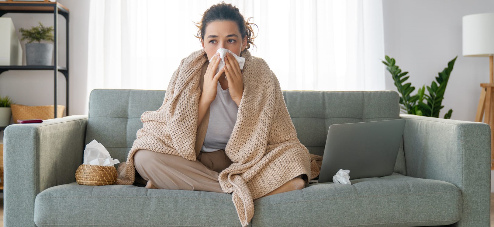 Photo d'une femme qui se mouche sur un canapé - Score de Congestion/Obstruction Nasale (SCN)