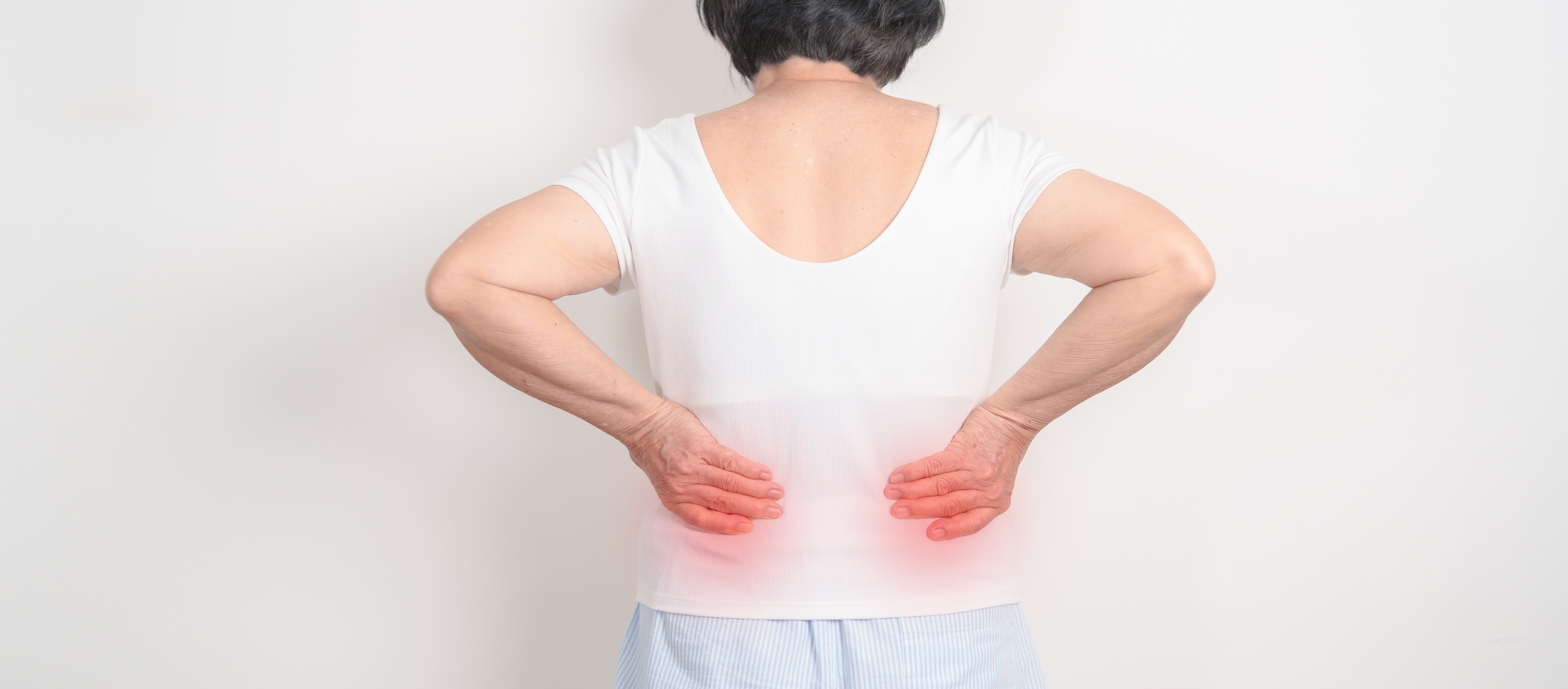 Person von hinten mit Händen am unteren Rücken und rotem Leuchten an den Nierenbereichen