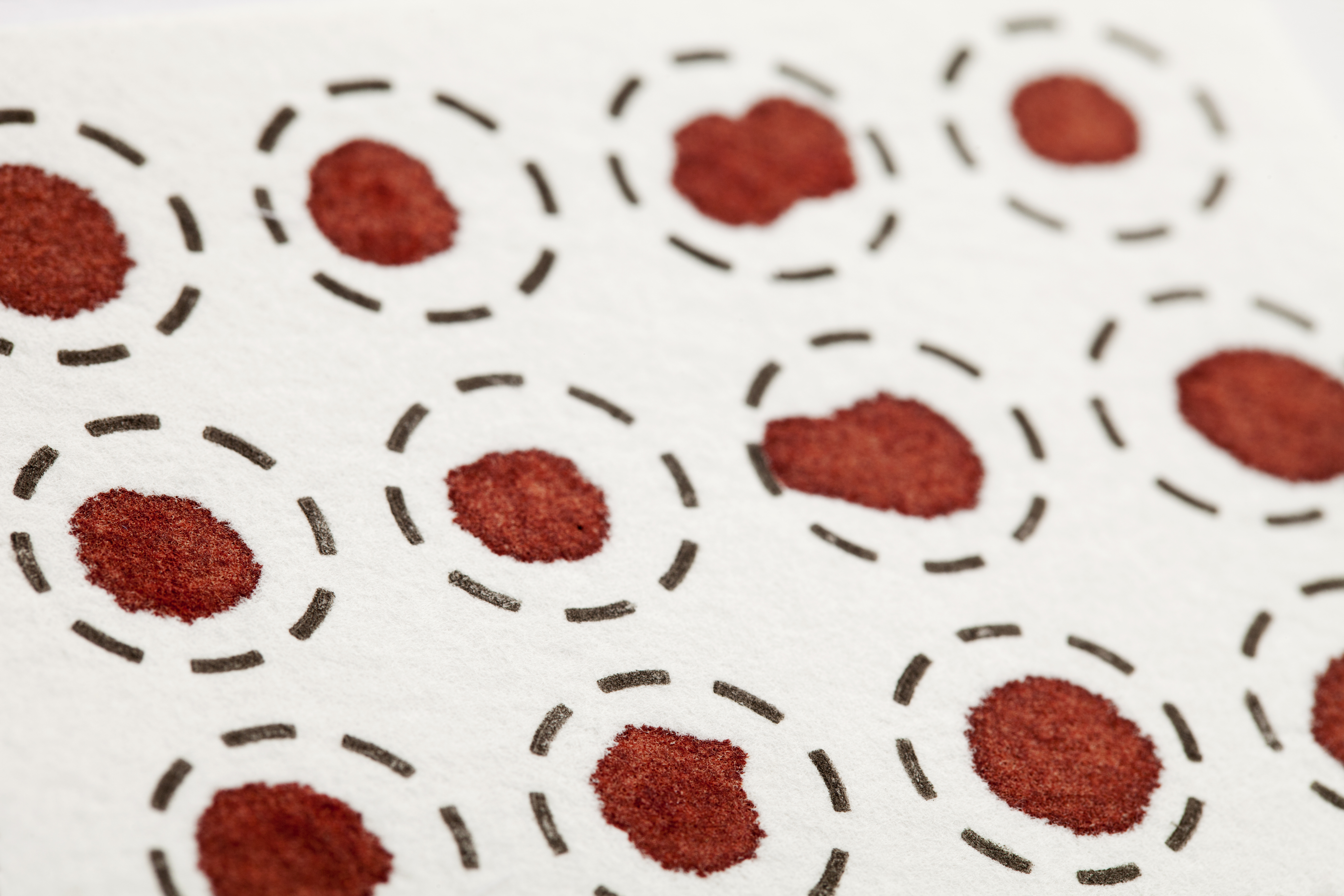 Mehrere rote Blutstropfen auf weißem Papier, umgeben von gestrichelten Linien