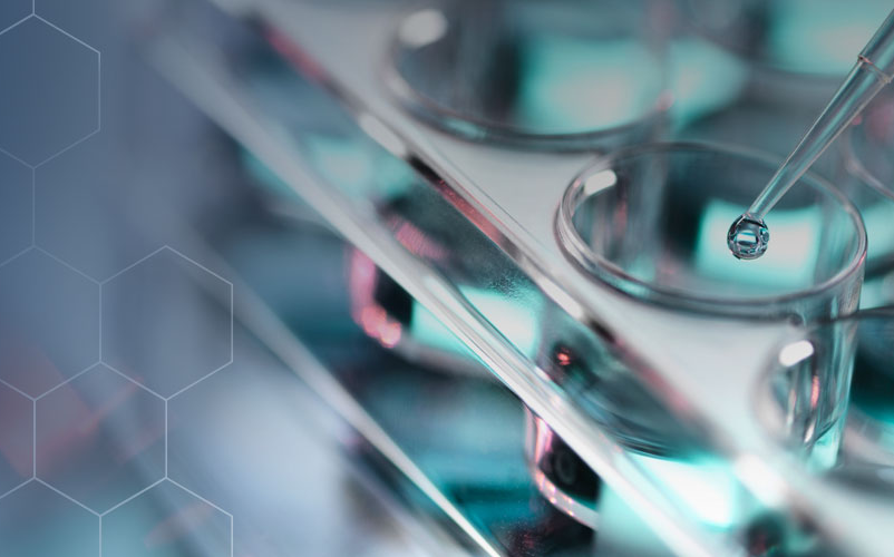 Close-up of a laboratory pipette dispensing liquid into a multi-well plate with a white outlined hexagonal pattern fading into the background.