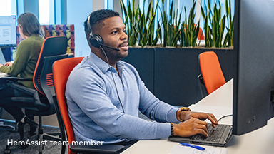 Portrayal of a smiling man sitting at a desk wearing a headset