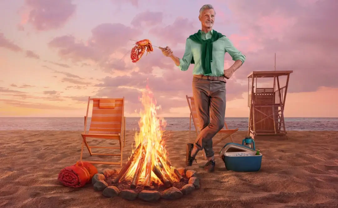 Older man standing next to a bonfire on the beach