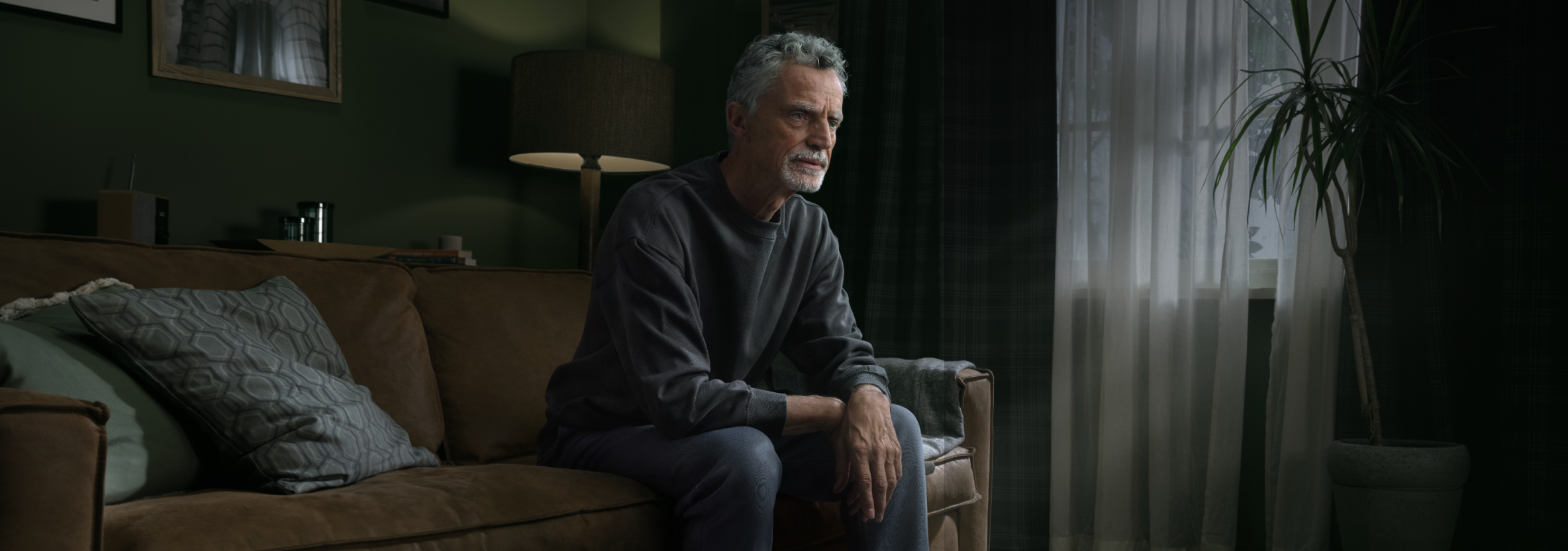 A concerned older man sitting on a couch
