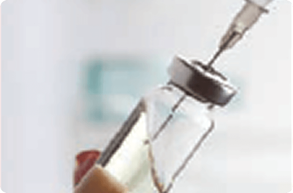 Image of syringe needle inserted into the rubber stopped medicine vial.
