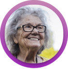 Portrait of a smiling woman with gray hair and glasses, framed in a purple circle.